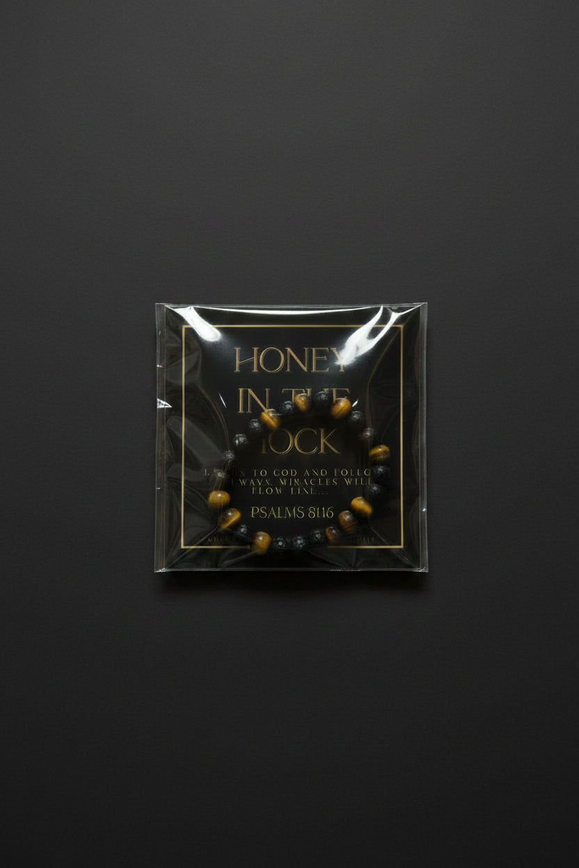 A hand holding a packaged beaded bracelet with a black background card that reads 'HONEY IN THE ROCK' and 'PSALMS 81:6'. The bracelet itself appears dark brown or black with small gold and red accents.
